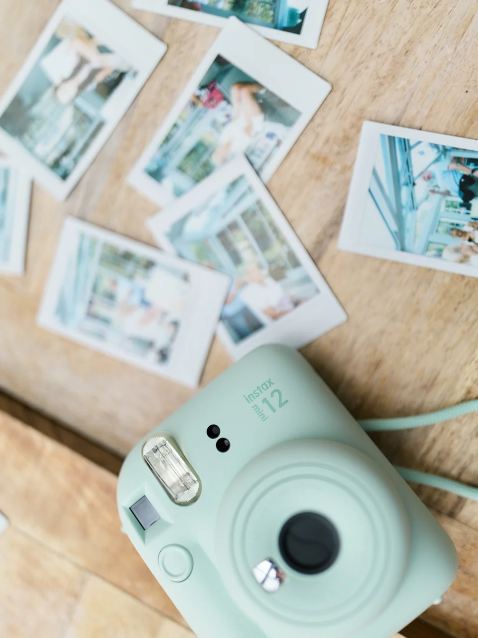 An instant camera beside small photographic prints